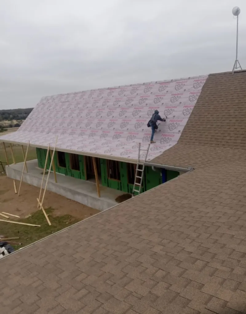 Worker preparing underlayment for a metal roof installation in Tallulah